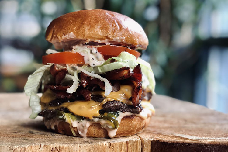 The Caramba Burger is an impressive double patty stack, bursting with bacon, melted cheese, tomatoes and lettuce.