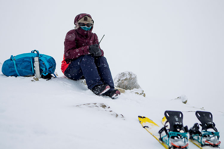 A snowshoer sits in the snow on a satellite phone in Whistler's backcountry.