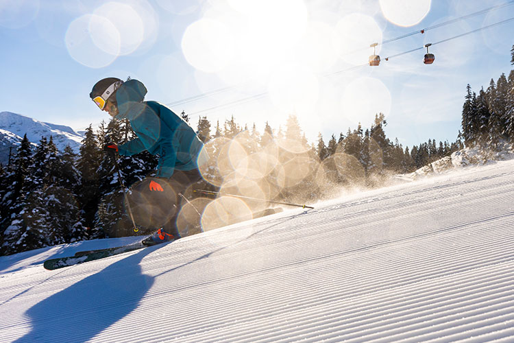 Skier on a groomed run in the sunshine in Whistler.