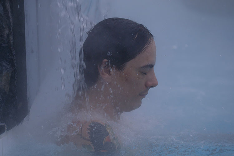 Court Larabee closes his eyes and relaxes under a warm waterfall at the Scandinave Spa Whistler.