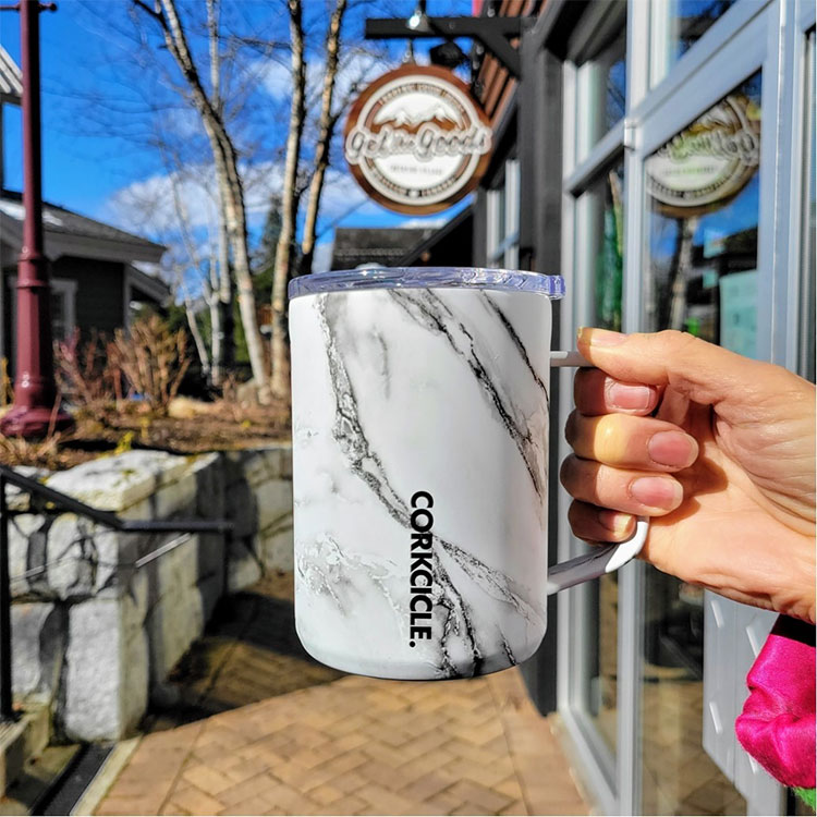 A woman holds a Corkcicle mug outside Get The Goods in Whistler.