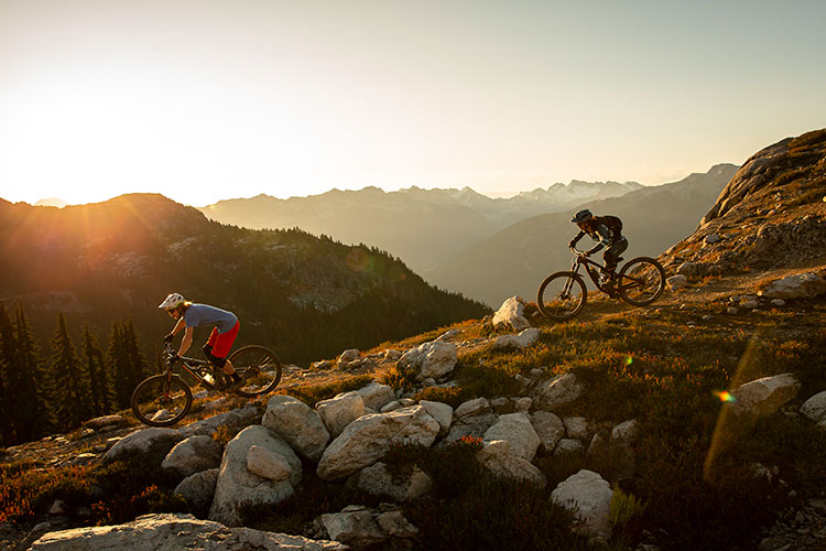 Two mountain bikers make their way down a trail in Whistler's high alpine as the sun begins to set.