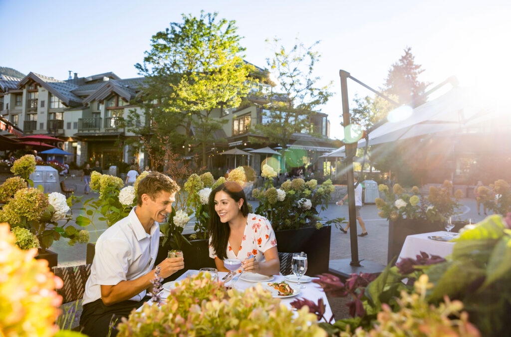 A couple dine on a sunny, outdoor patio in Whistler.