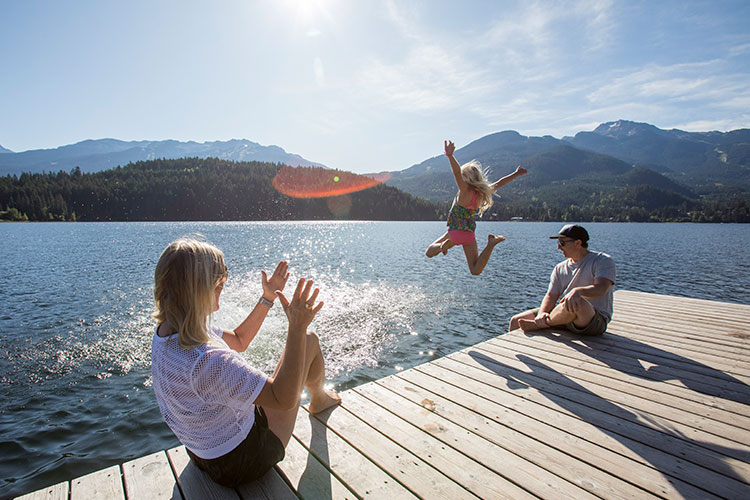 A child jumps into a lake in Whistler on a sunny day.