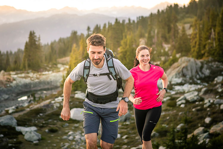 A man and woman trail run in the high alpine in Whistler.