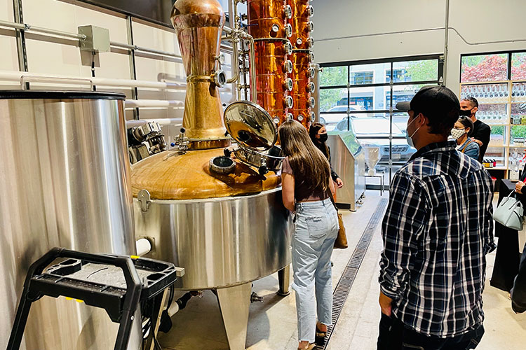 A group of people explore the distilling equipment on a tour of Montis Distilling in Whistler.