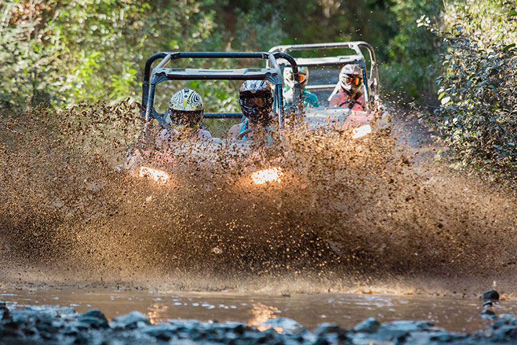 Two RZRs power through a muddy puddle in Whistler.