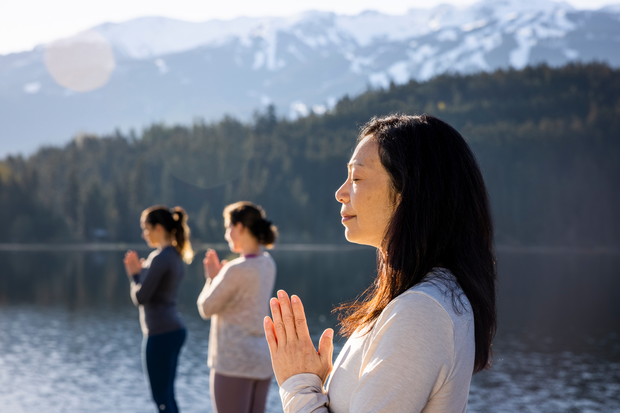 Three women do yoga on a dock in Whistler.