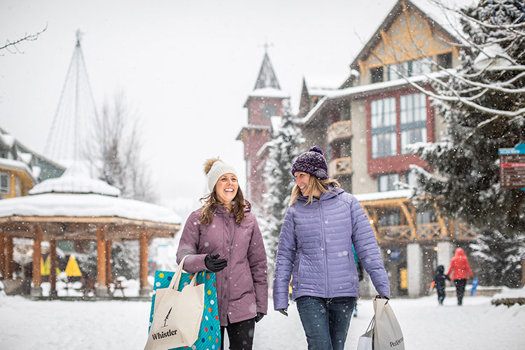 Two women carry shopping bags down the Village Stroll.