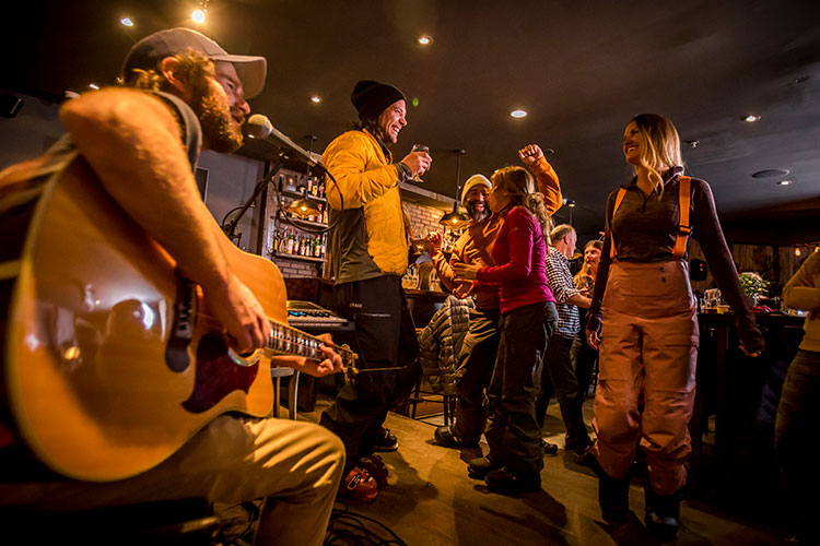 A group of skiers dance to live music at a bar in Whistler.