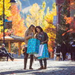 Two women walk down the Village Stroll in Whistler carrying shopping bags and enjoying the fall colours.