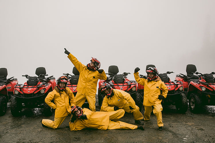 A group of women in yellow waterproof gear post for the camera on an ATV trip in Whistler.