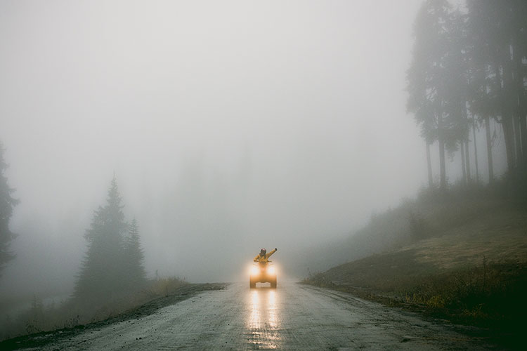 An ATV rider comes up a misty path in Whistler.