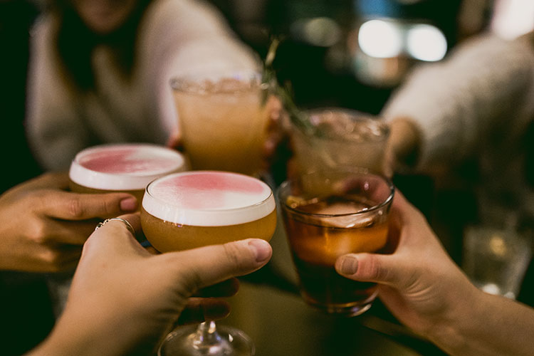 Five hands with a cocktail in each cheers to a weekend away in Whistler.