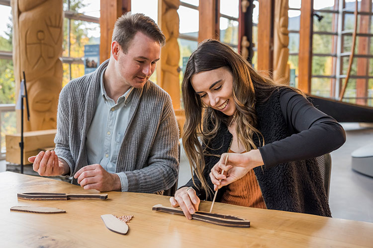 A couple do a wood craft at the Squamish Lil'wat Cultural Centre.