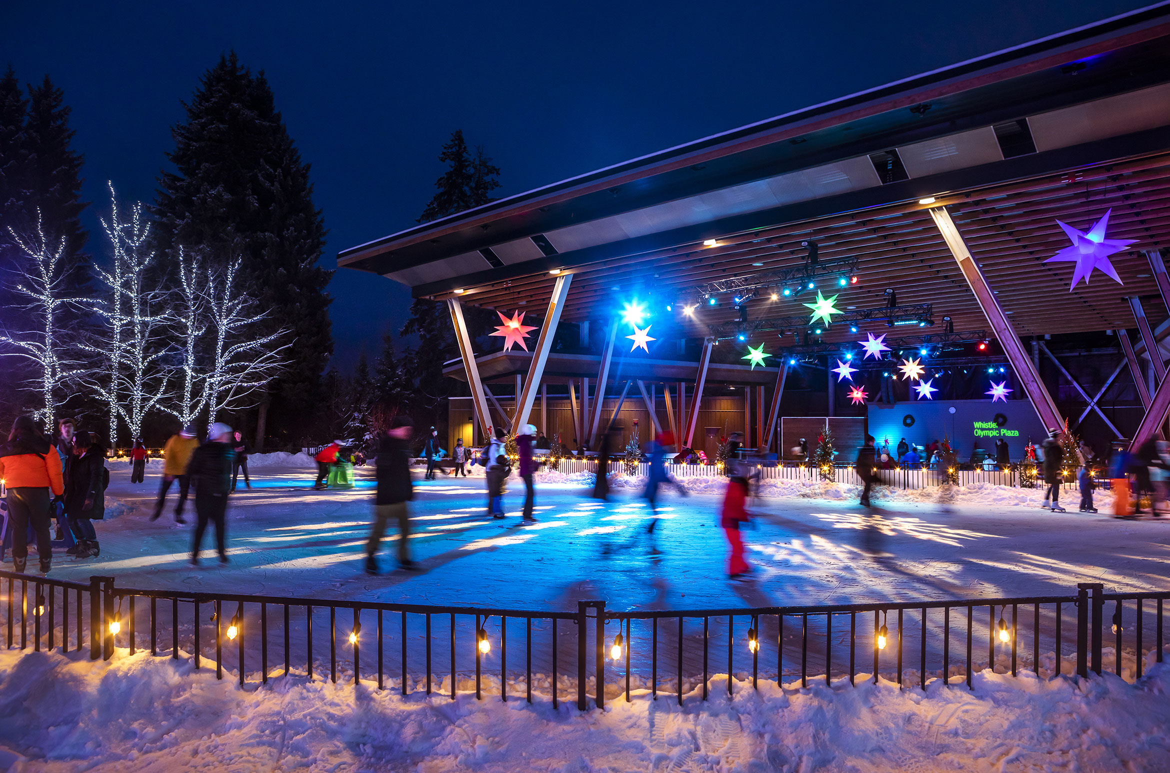 People ice skating at Olympic Plaza in Whistler in the evening.