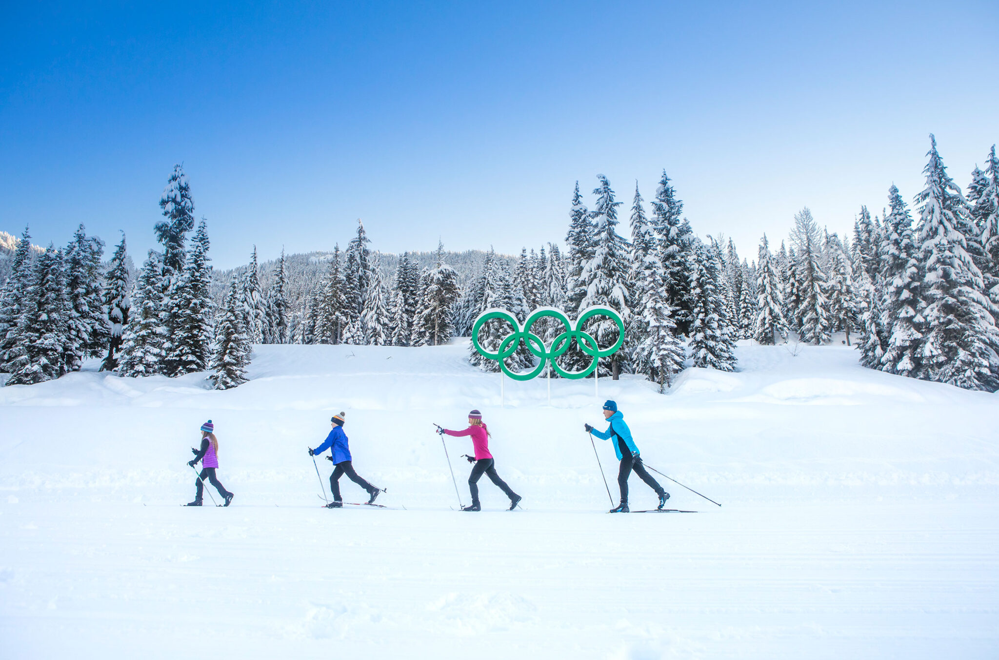 A family cross-country ski past the Olympic rings in Whistler.