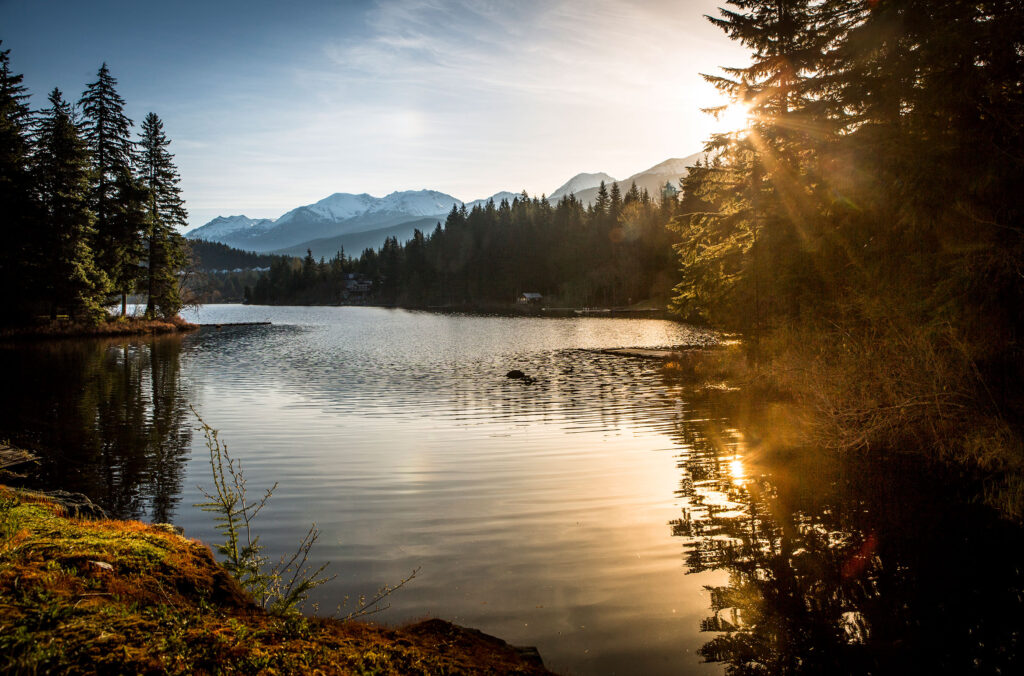 Sun dances on the glassy surface of a lake in Whistler.