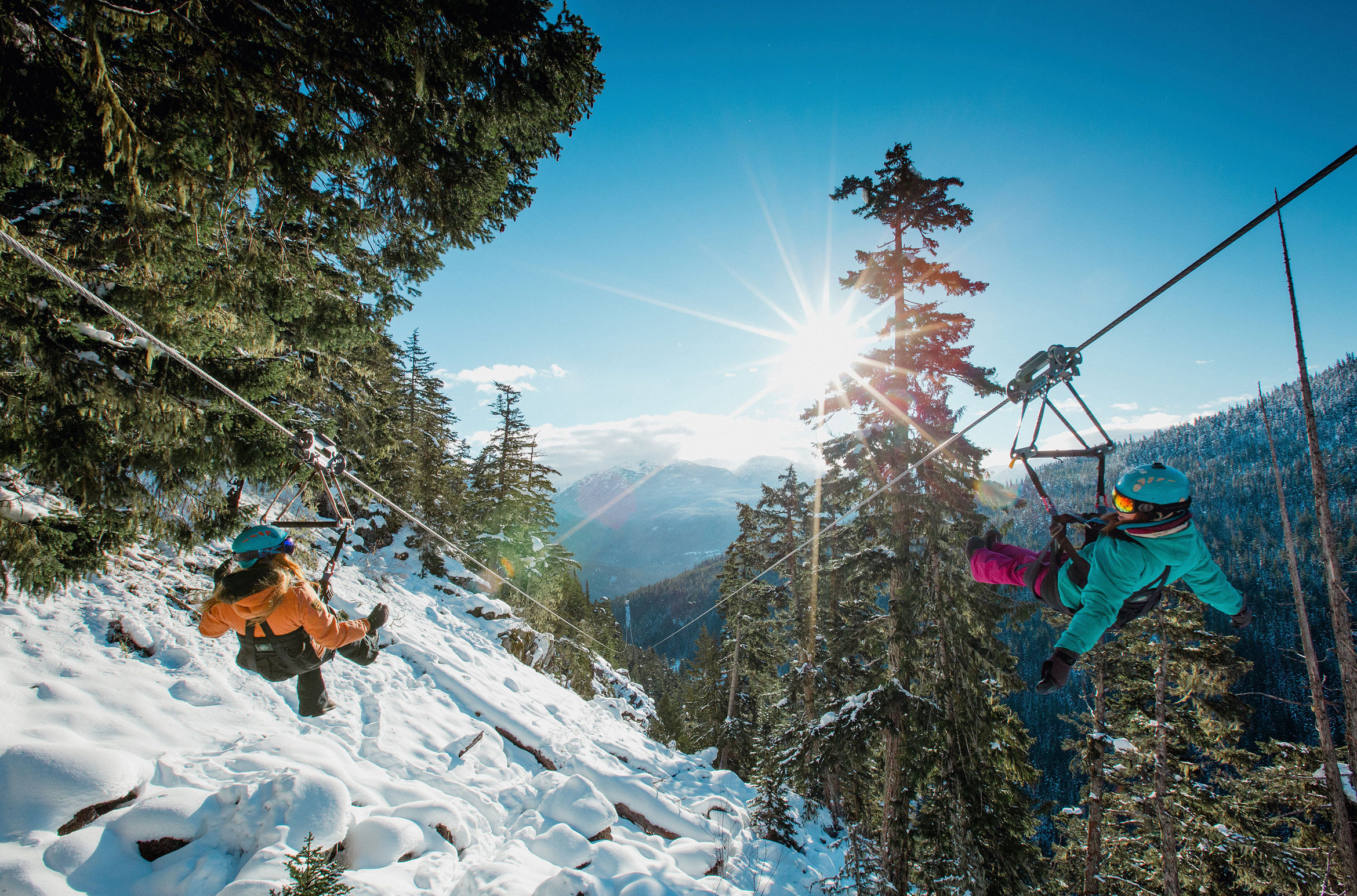 A woman and child zipline in the sunshine in Whistler.