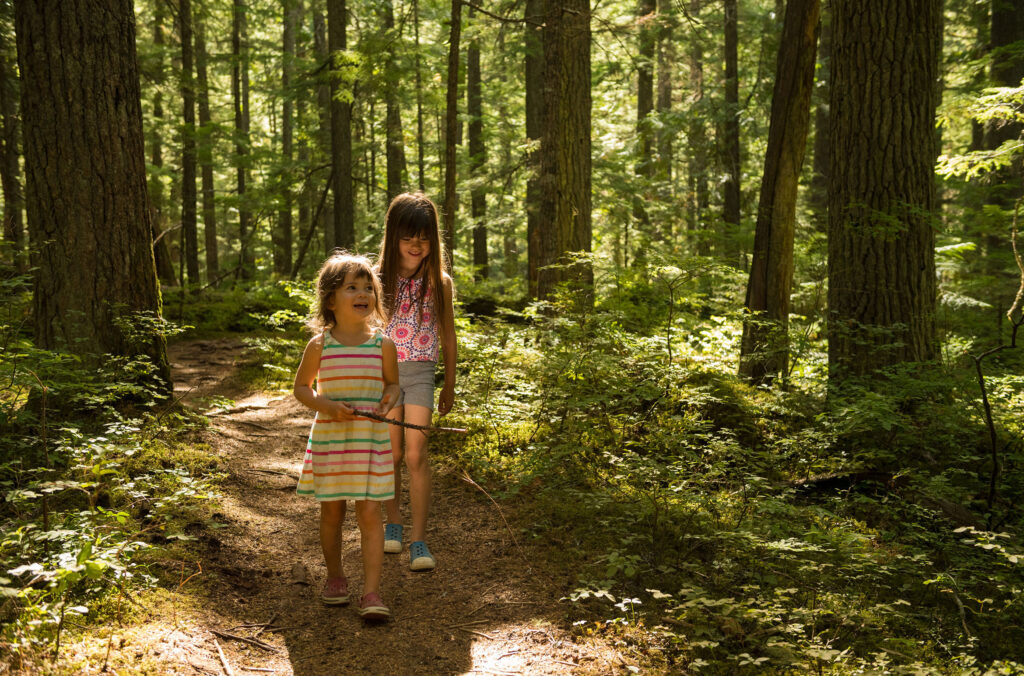 Two kids walk through the lush, green forest in Whistler.