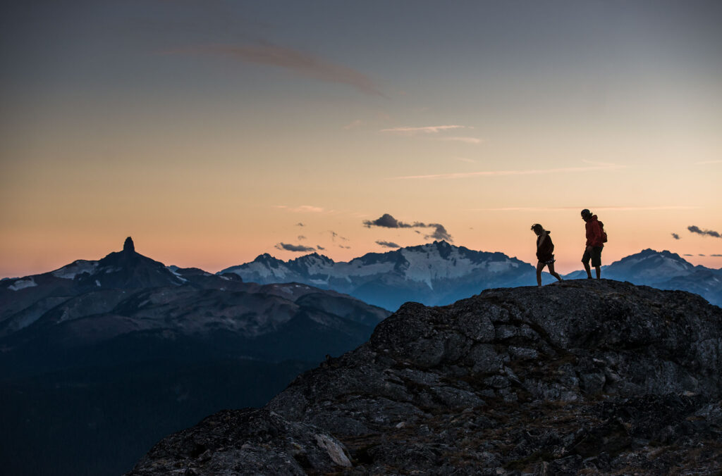 Hikers on Whistler Blackcomb with views out over the Coast Mountains enjoying the midweek stillness.