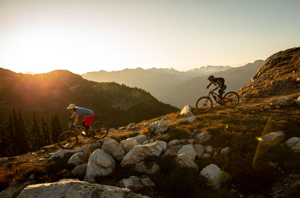 Two bikers head down the mountain in the afternoon sunshine. Less crowds midweek in Whistler.