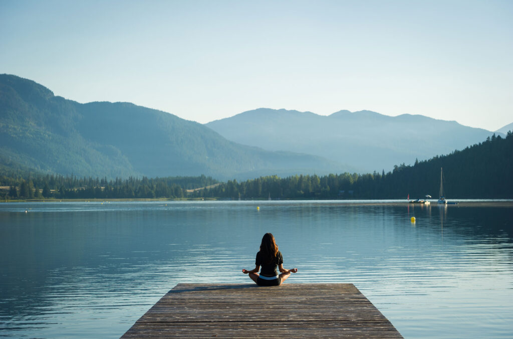 A woman sits on the edge of a dock overlooking Alta Lake in Whistler during the quiet of a summer midweek.