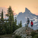 Two hikers admire the view of Black Task when hiking on Whistler Mountain in the summer.