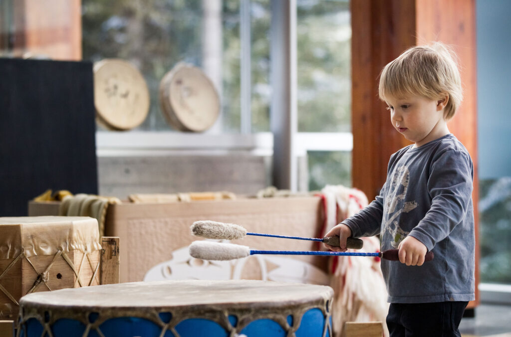 A young child plays the pow wow drum at the SLCC in Whistler.