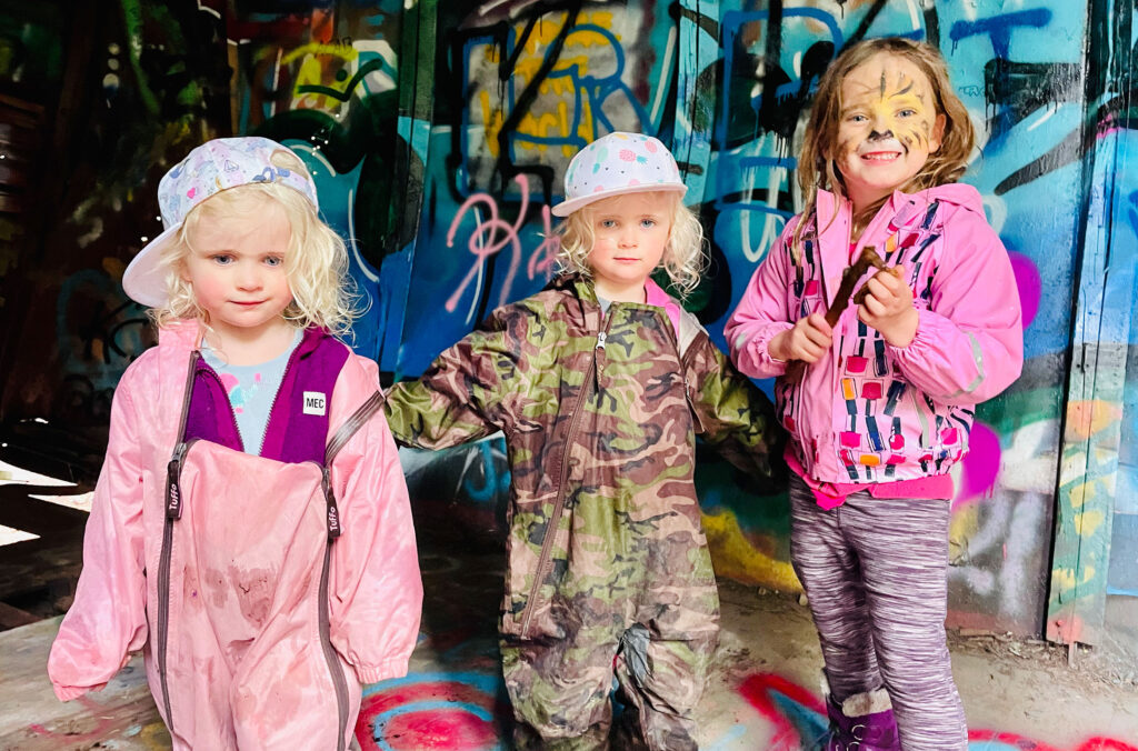 Three young kids stand in one of the old train cars at the Train Wreck in Whistler.