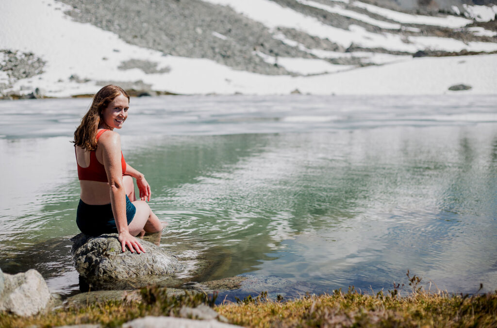 A hiker dips their feet in the cool waters of Blackcomb Lake on Blackcomb Mountain.