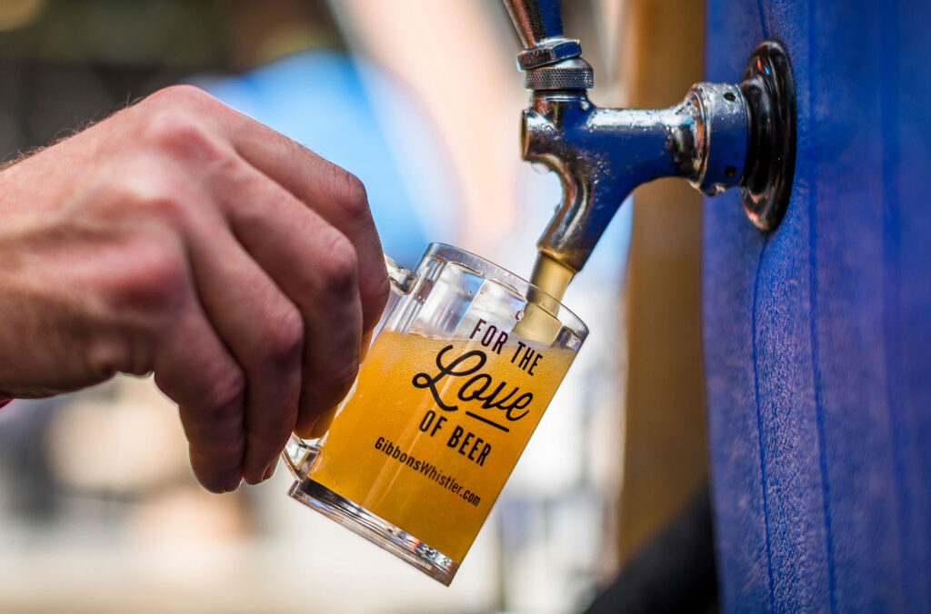 Beer is pouring into a tasting mug at the Whistler Village Beer Festival.