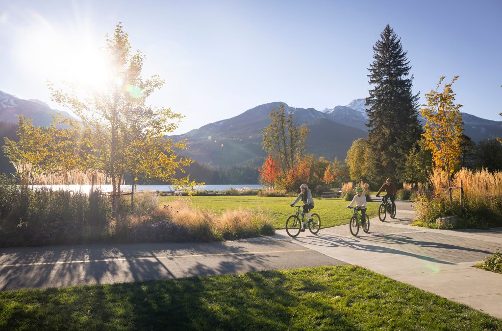 A family bikes along the Whistler Valley Trail in the fall sunshine.