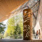 A couple look up at the artwork outside the Audain Art Museum in the fall sunshine in Whistler.