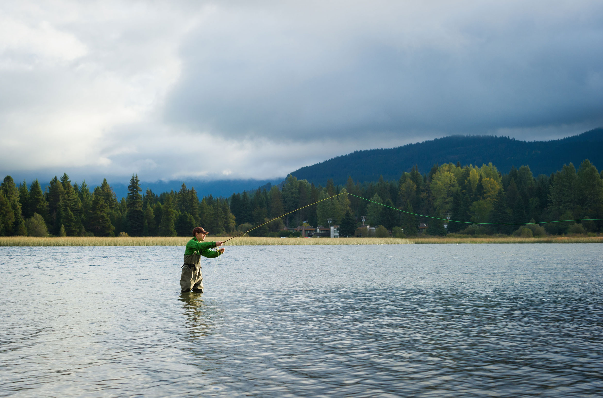 A man fishes in Green Lake in Whistler.