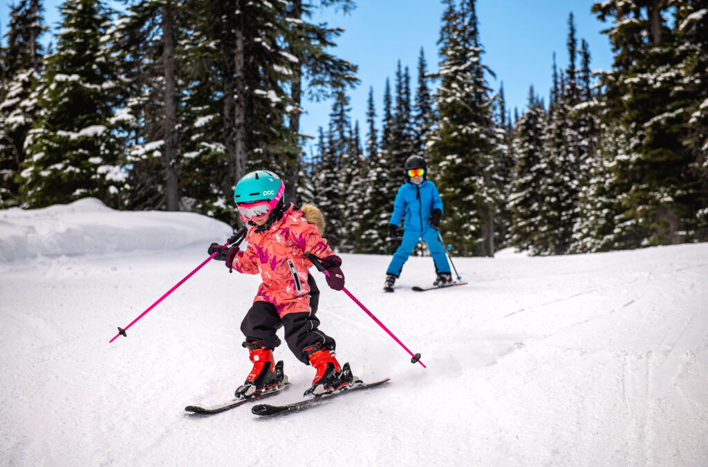 Two kids ski down the slopes on Whistler Blackcomb.