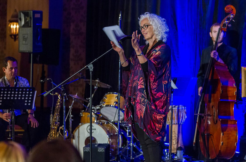 An author reads her work on a stage while musicians play at the Whistler Writers Festival.