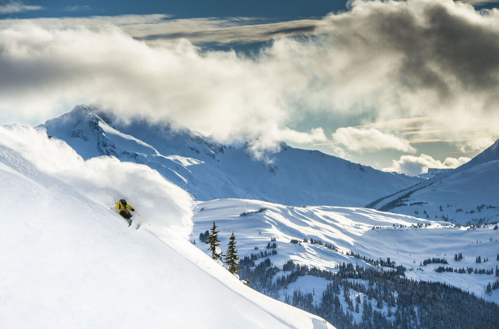 A skier makes their way down a steep, powdery slope on Whistler Blackcomb.