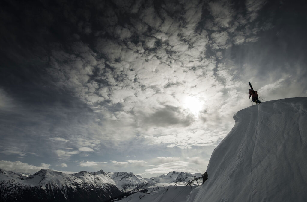 A skier hikes up to an inbounds ridge on Whistler Blackcomb.
