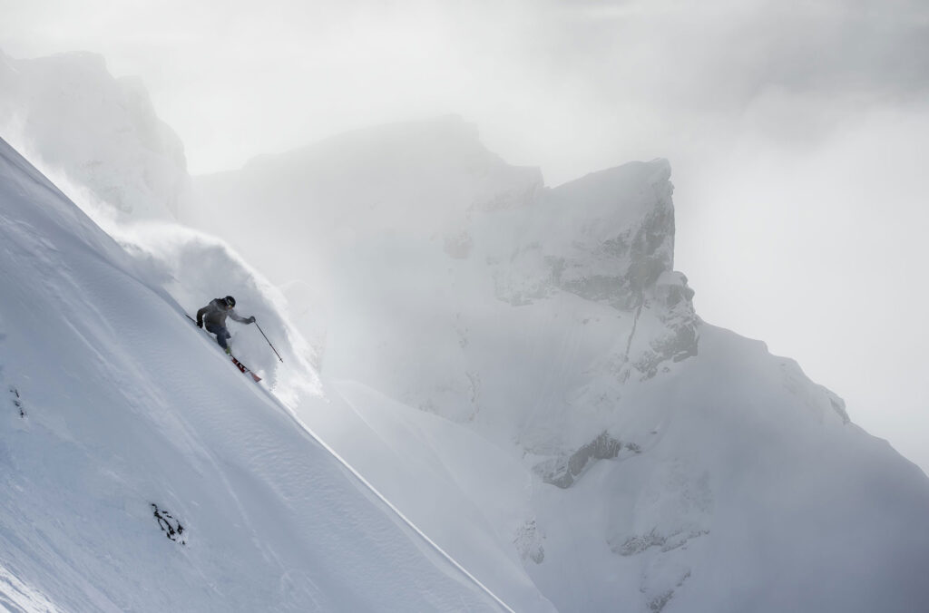 A skier makes their way down a steep, powdery slope on Whistler Blackcomb.
