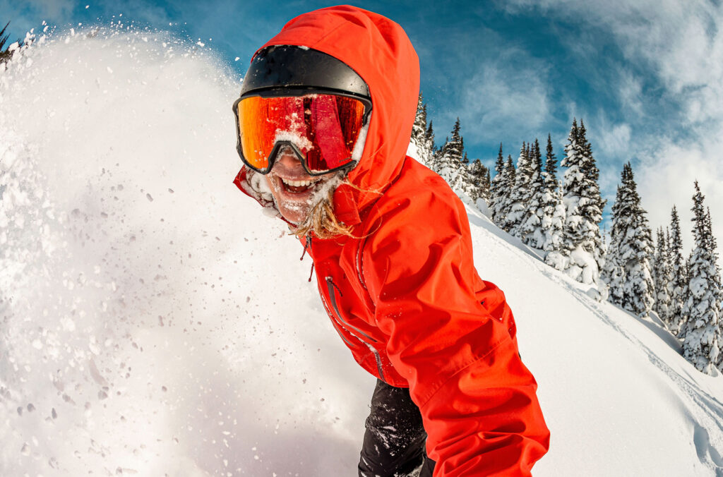 A snowboarder grins as they power through the powder on Whistler Blackcomb.