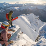 Two snowboarders look out over the expanse of the mountains at Whistler Blackcomb.