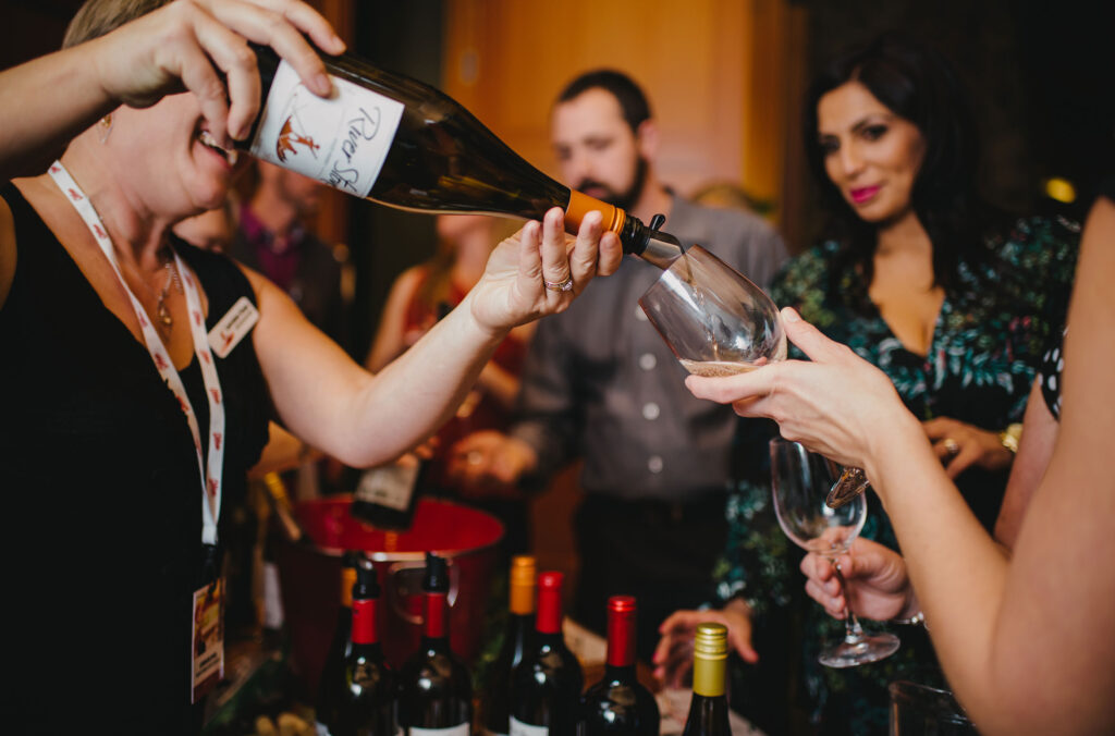 A woman pours a glass of wine for an event-goer at Whistler Cornucopia.