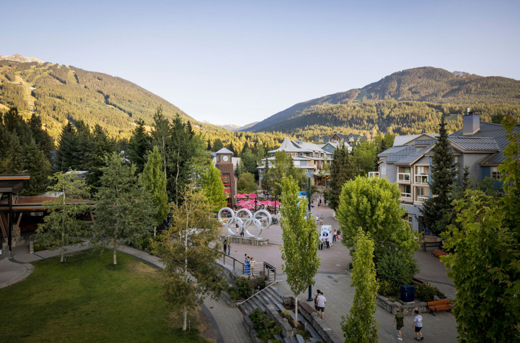 Aerial shot of Whistler Village showing Whistler Olympic Plaza up to Whistler and Blackcomb Mountains in the spring.