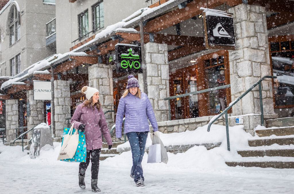 Two women walk down the snowy Village Stroll in Whistler.
