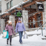 Two women walk down the snowy Village Stroll in Whistler.