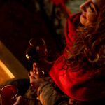 A woman drinks a glass of wine by a fire in Whistler.