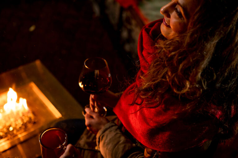 A woman drinks a glass of wine by a fire in Whistler.