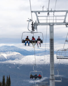 Three skiers on a chairlift waiting to hit the slopes on the opening day of Whistler Blackcomb.