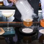 A bar tender presents three amazing cocktails on the bar of the Mallard Lounge at the Fairmont Chateau Whistler.